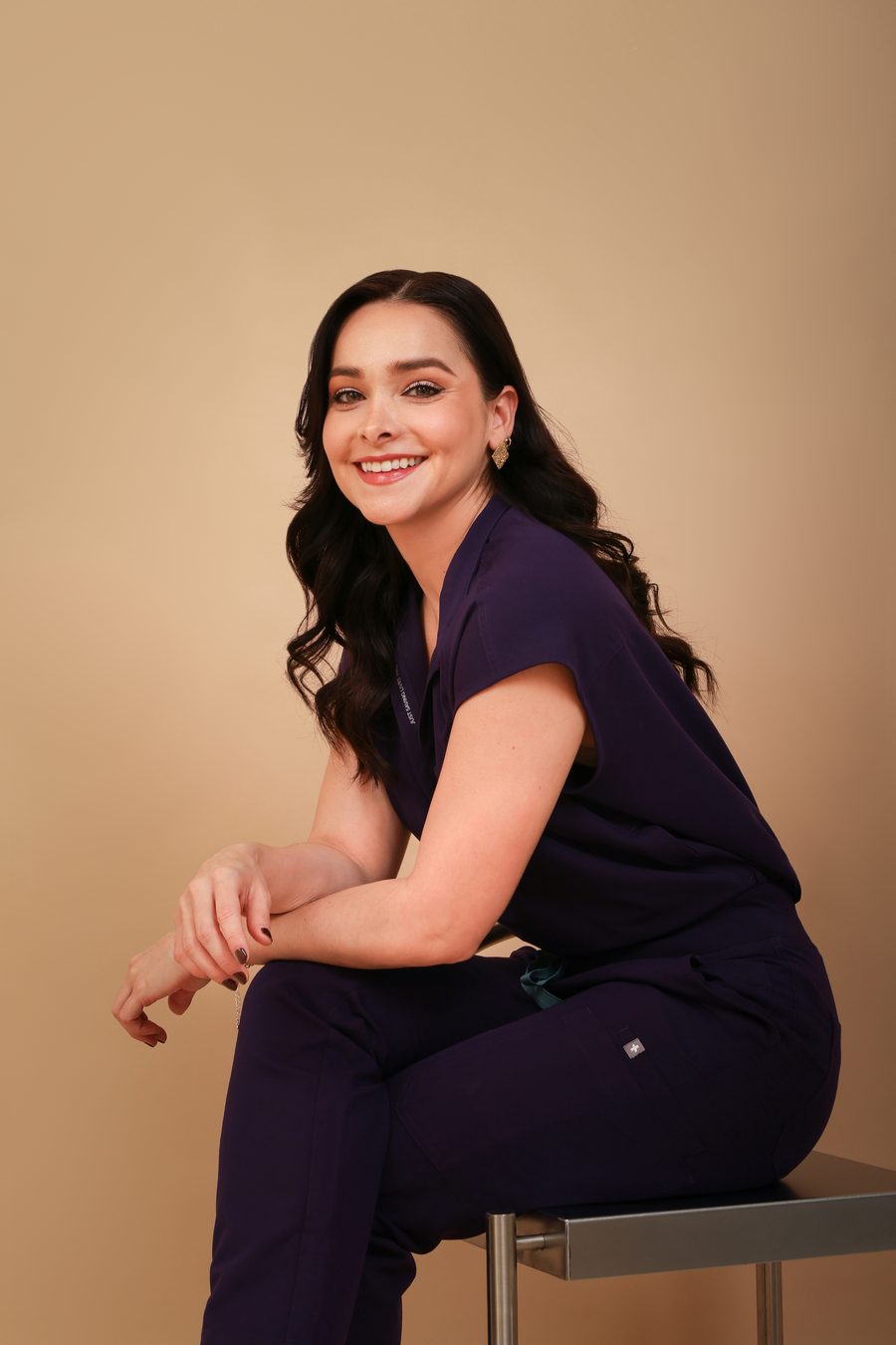 Dra. Lizbeth Ortega con uniforme médico morado, sentada
