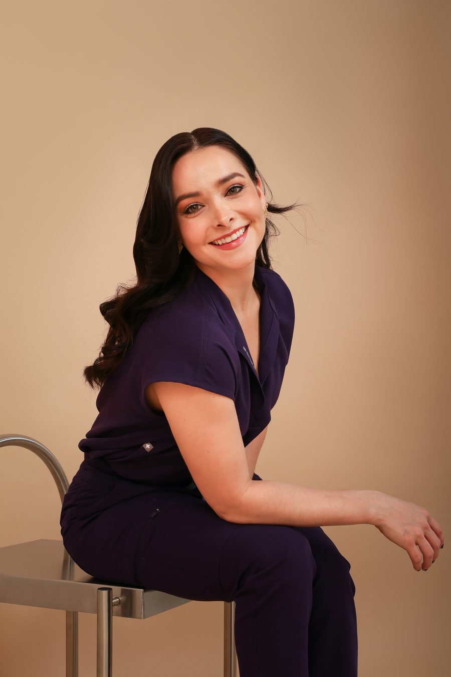 Dra. Lizbeth Ortega con uniforme médico morado, de perfil